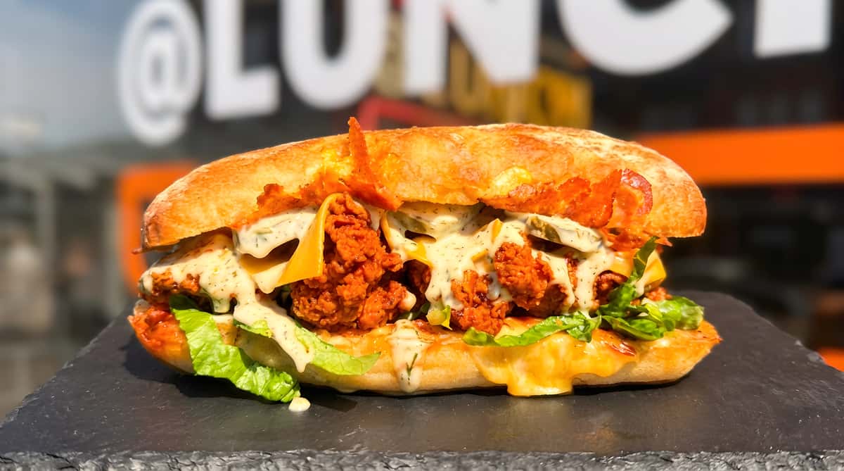 @Lunch crispy fried chicken sandwich with melted cheese, lettuce, pickles, and creamy herb sauce