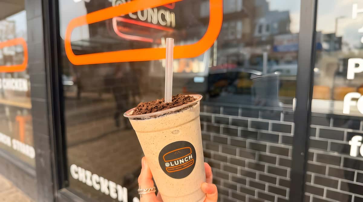 @Lunch creamy chocolate milkshake topped with chocolate crumbs in a branded takeaway cup