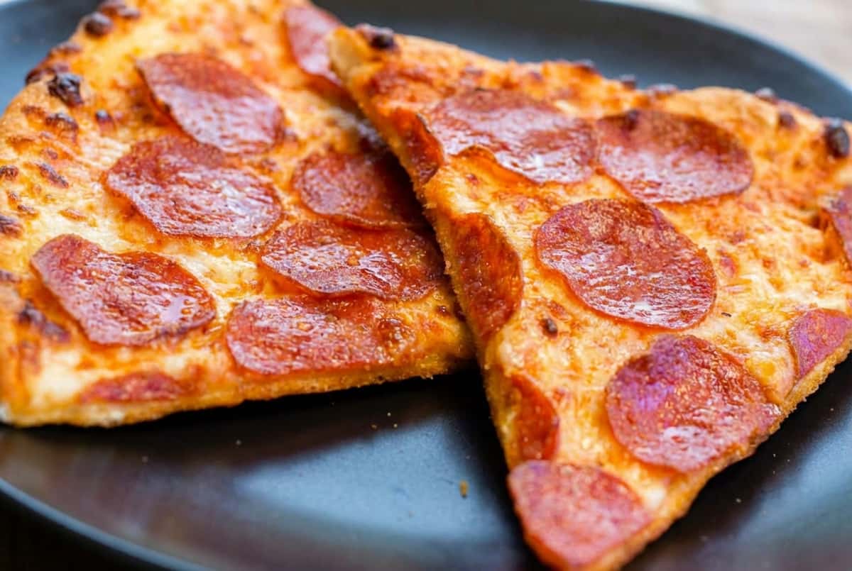 Close-up of two pepperoni pizza slices showing crispy crust and bubbling cheese.