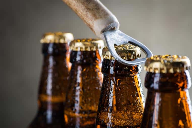 top view of four bottles of beer with one being open