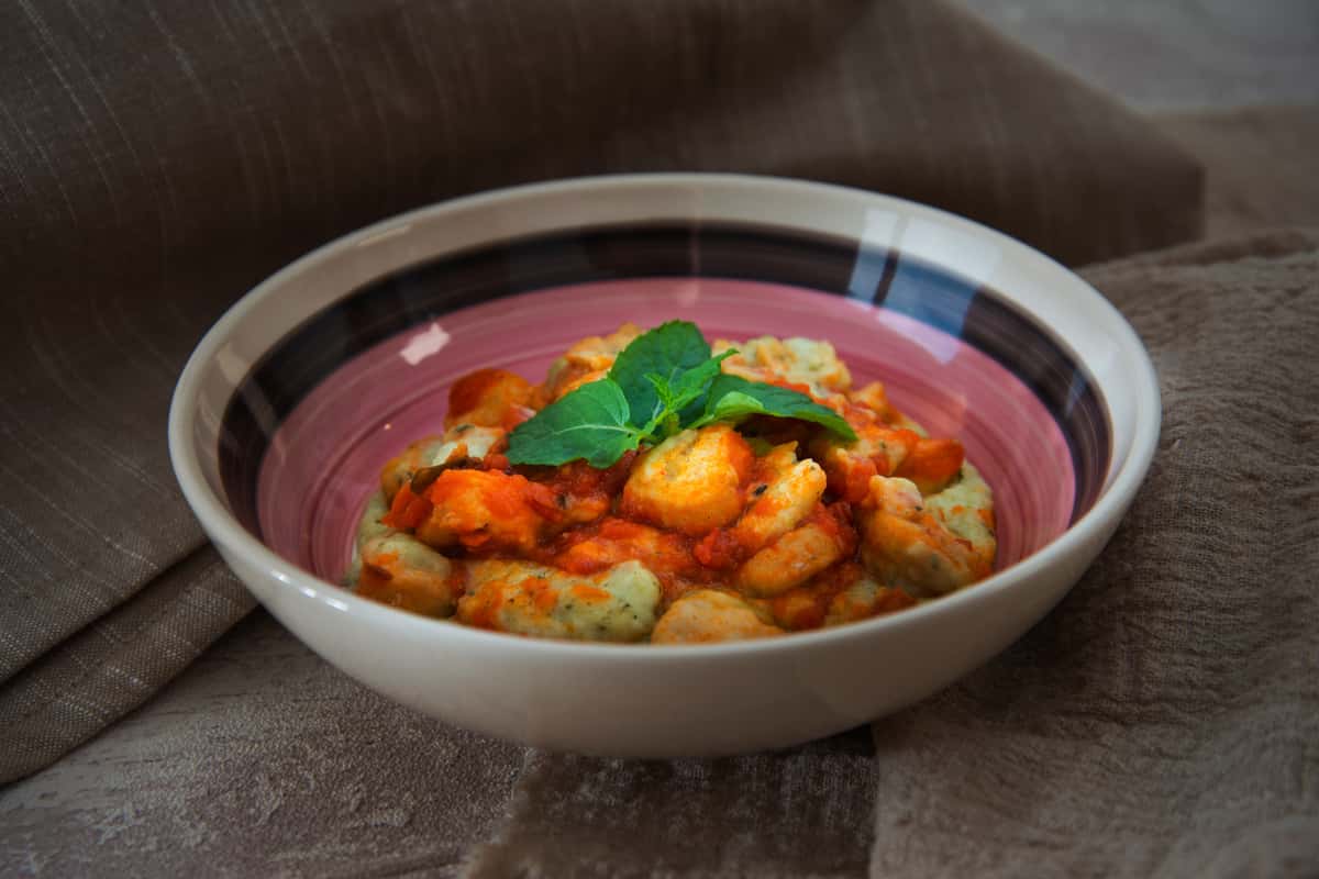 Shrimp cooked in a rich curry sauce, garnished with fresh herbs and served in a ceramic bowl.