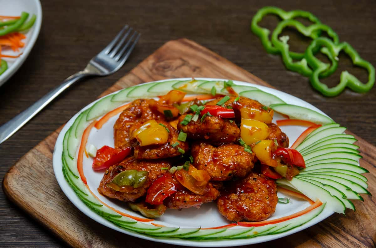 Shrimp stir fried with vegetables and sauce, served on a patterned plate.