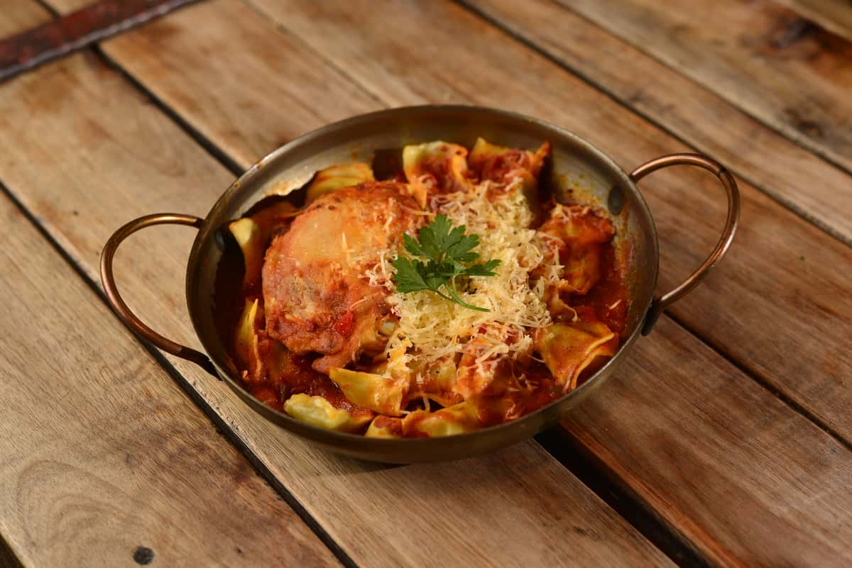 Chicken curry cooked with spices, served in a rustic bowl on a wooden table.