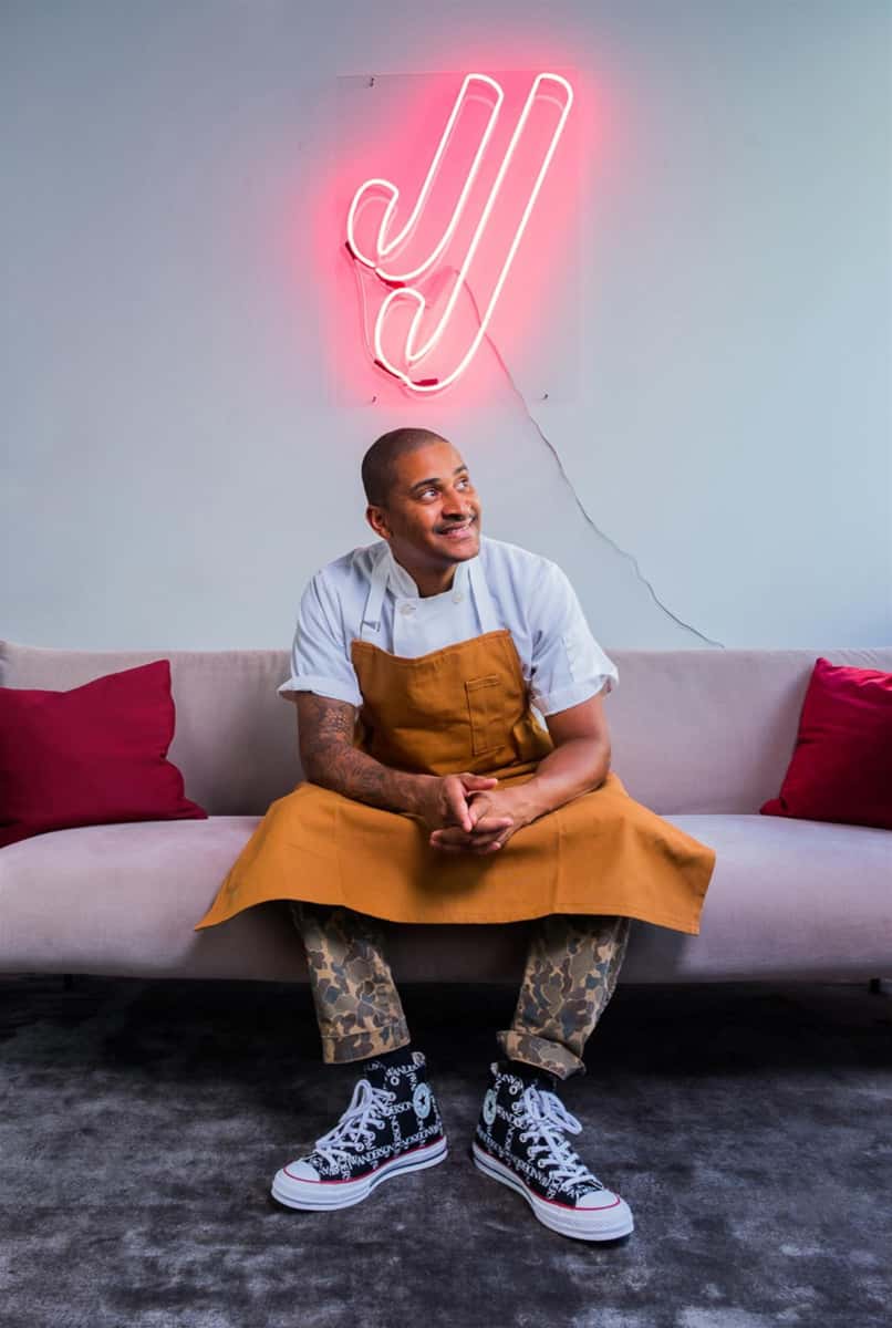 Chef JJ sitting on a sofa with a "JJ" light behind