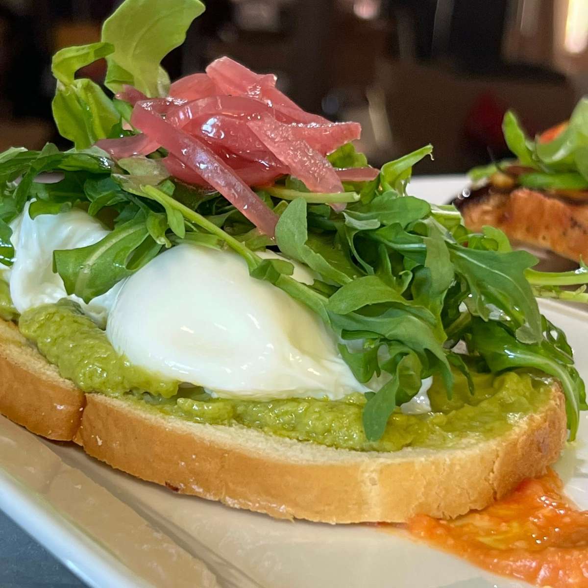 Two Eggs Poached, Pickled Red Onion, Arugula with Red Pepper Hummus on Toasted Sourdough