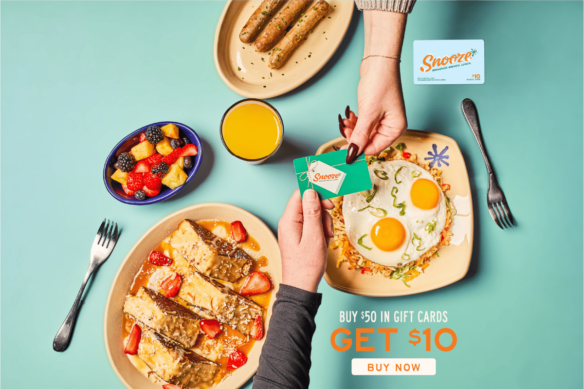 Hands exchanging a gift card over plates of breakfast food