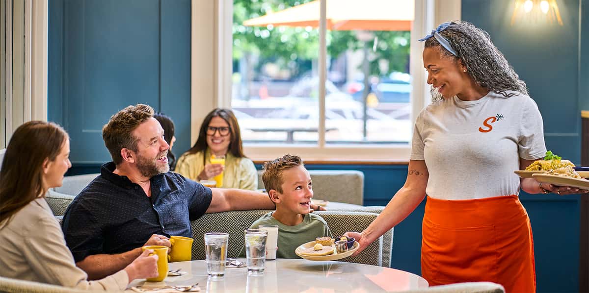 guest diners getting food placed on table inside store.jpg
