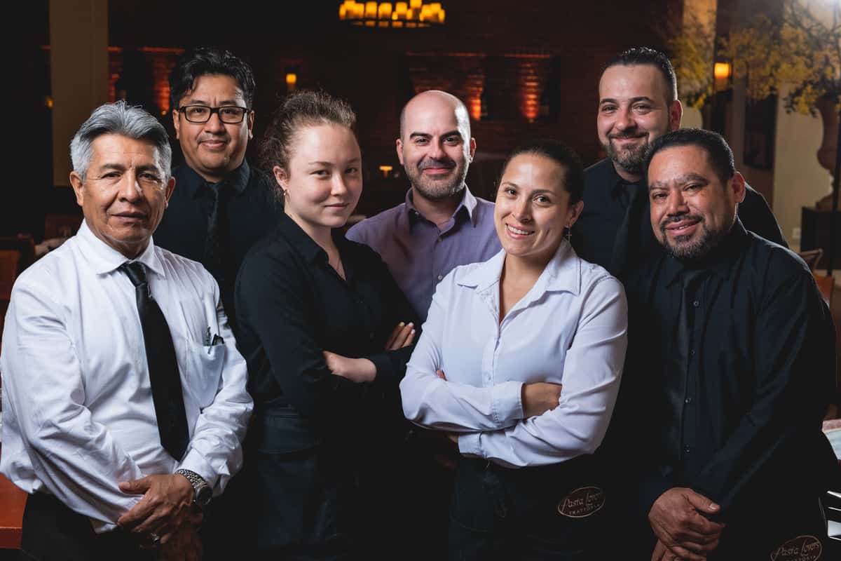 Five smiling Pasta Lovers Trattoria team members standing together inside the restaurant, dressed in professional attire, showcasing the welcoming hospitality of the family-owned Italian restaurant in Midtown Manhattan, NYC.