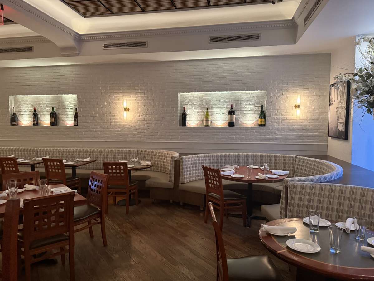 Spacious private event cellar at Pasta Lovers Trattoria in Times Square, NYC, featuring neatly arranged dining tables, brick walls, and soft ambient lighting.