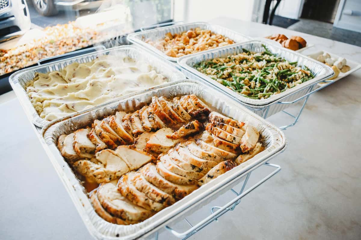 Thanksgiving catering pans of turkey, mashed potatoes, green bean caserole, and stuffing