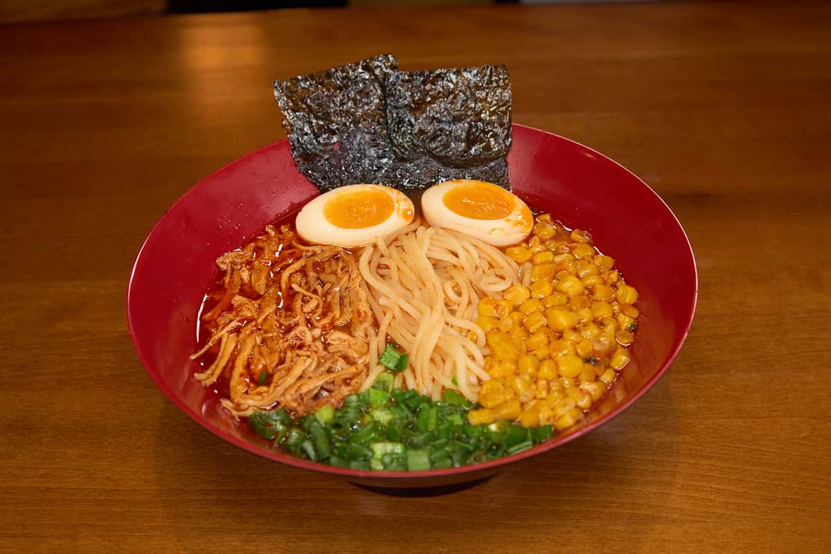 Ramen in spicy miso chicken, pork and vegetable broth, topped with shredded chicken, corn, sesame seeds, soft boiled egg, scallion, roasted seaweed and chili oil