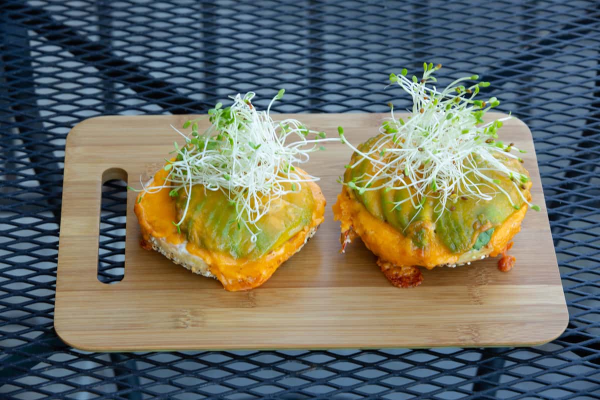 open-faced sandwich topped with melted cheese and fresh microgreens on toasted bread