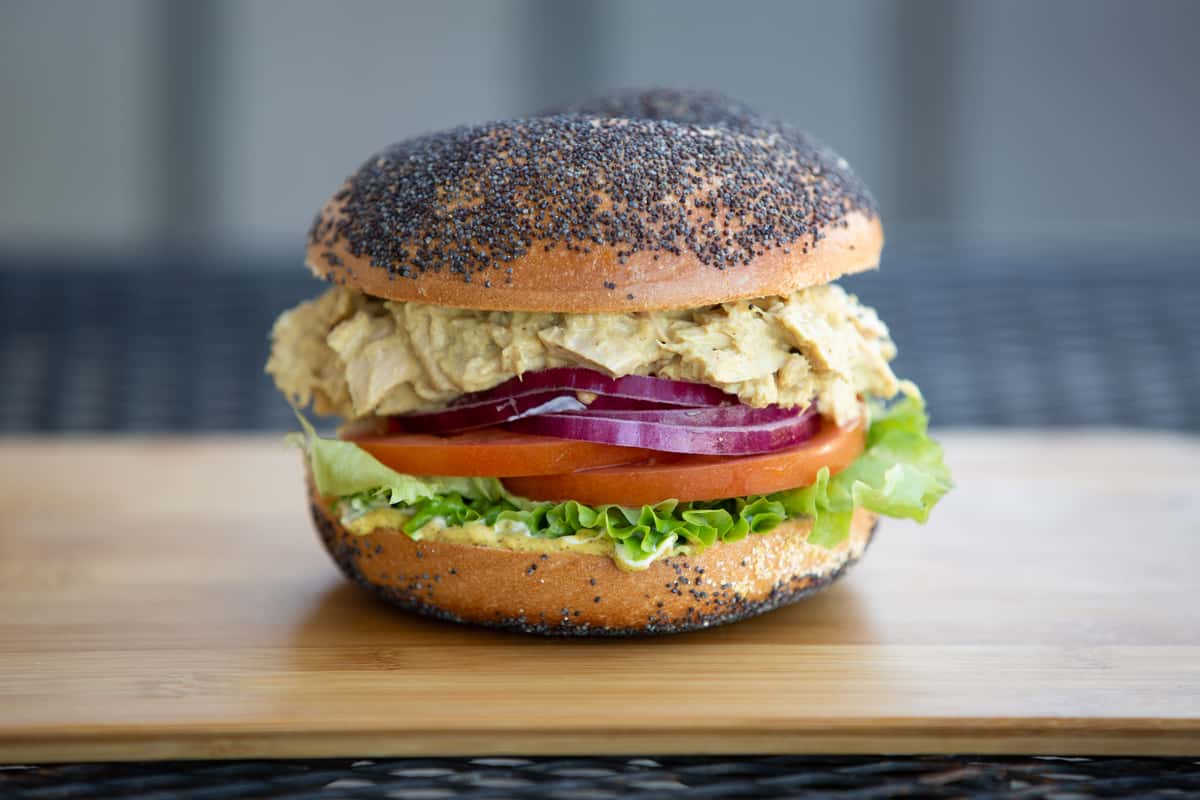 crispy fish sandwich with lettuce, tomato, and creamy sauce on a seeded bun