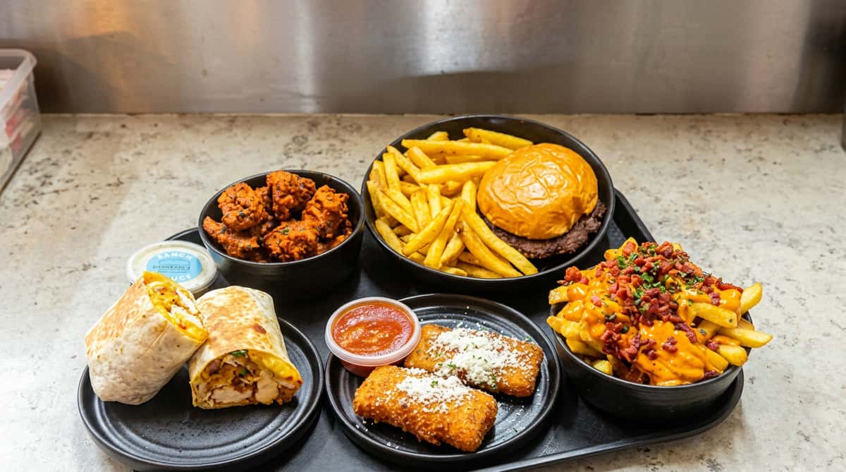 Food platter with chicken, wraps, fries, and sauces