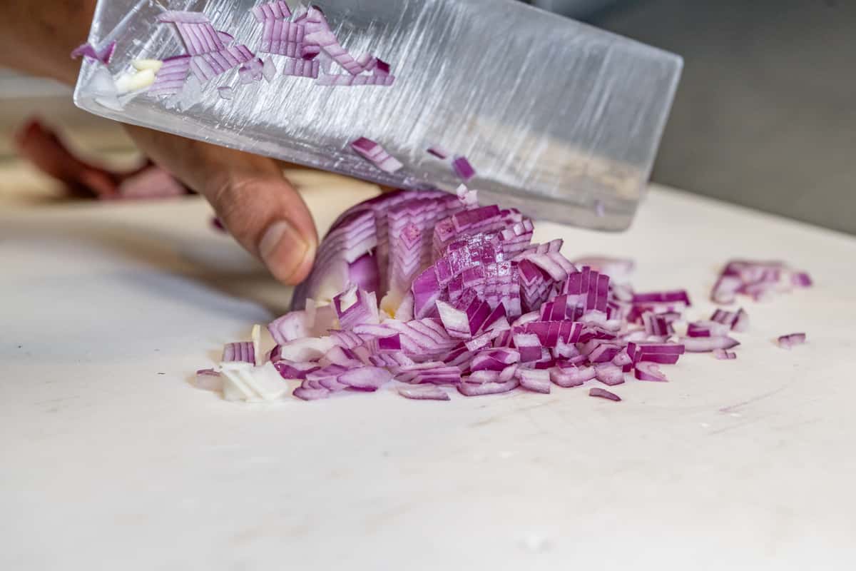 Chef slicing red onion