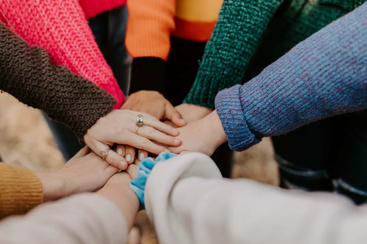 Group huddling together with their hands laid on top of one another