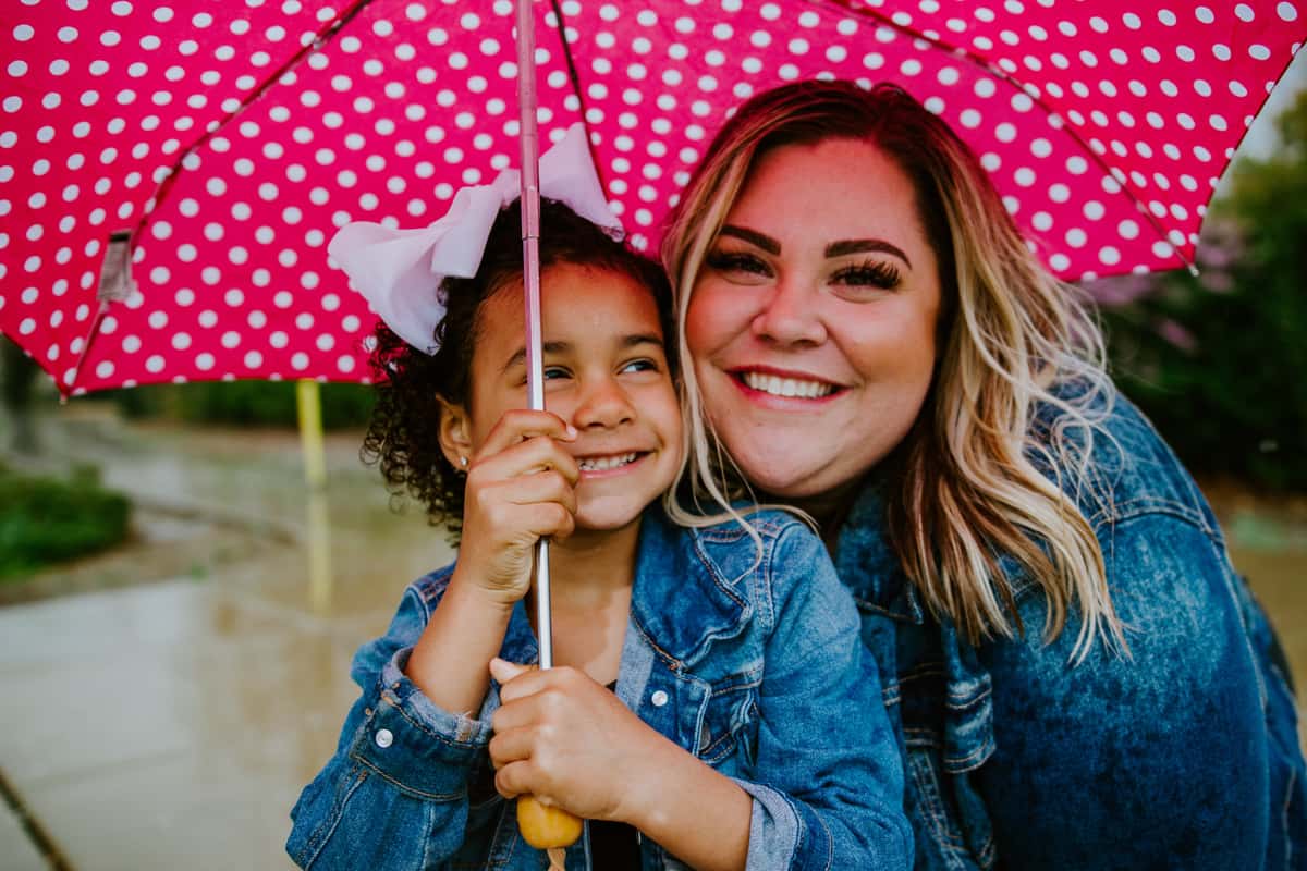 Smiling woman and child with a hot pink polka dot umbrella