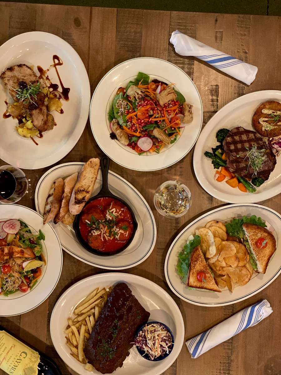 Delicious meal featuring steak, ribs, salads, and more on a table at KP's Kitchen & Market.