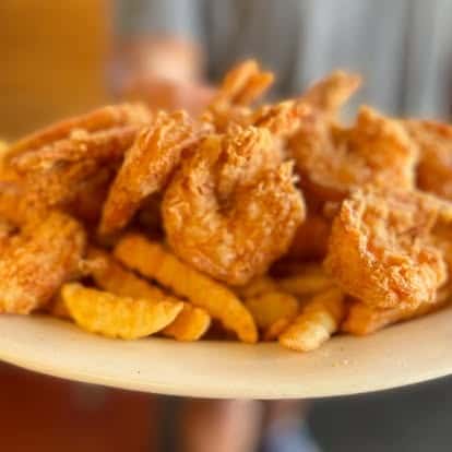 Plate of crispy golden fried shrimp paired with thick crinkle-cut fries, showcasing classic Southern-style seafood.