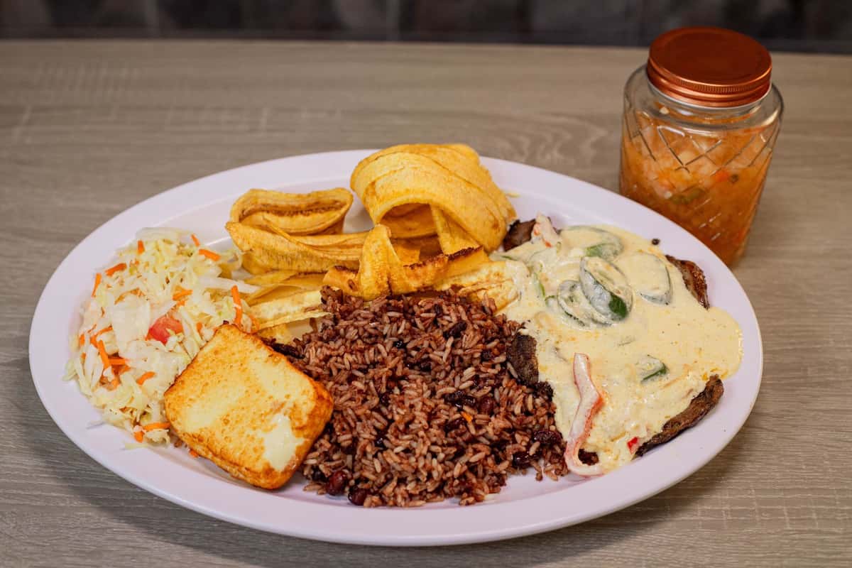 It's a 8 oz Ribeye Steak, served with a creamy sauce, slices of jalapeno, bell pepper and onions, Gallo pinto, Handmade Plantain chips or sweet soft plantain, fried cheese and cabbage salad