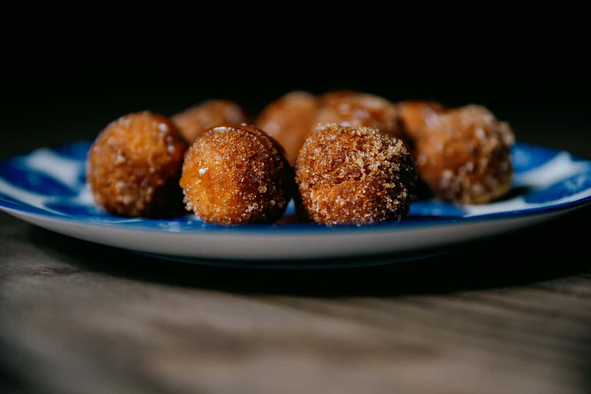 Cinamon sugar donut holes sit on a blue plate