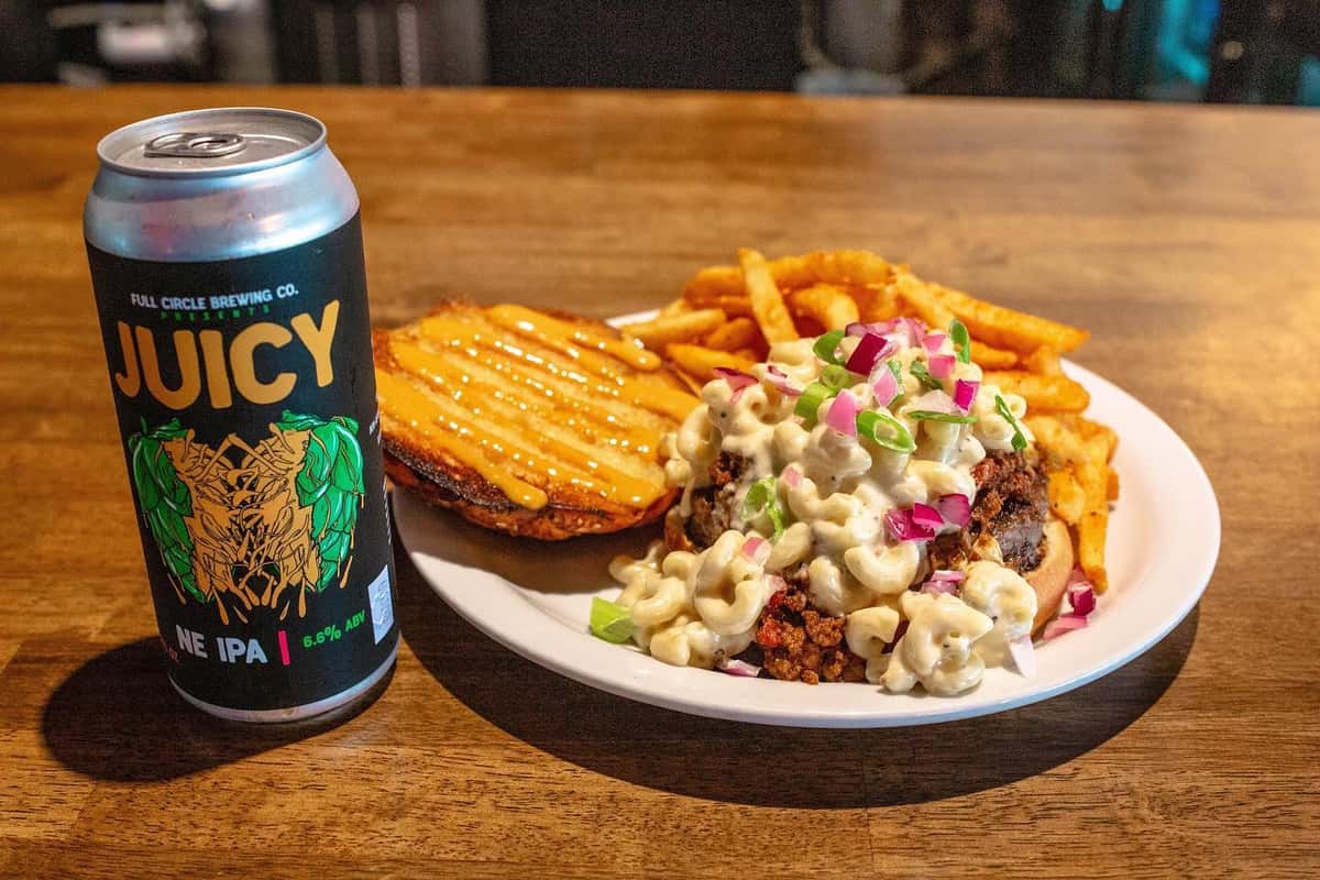 Hamburger with a unique pasta topping, grilled bun with crisp fries and a cold craft beer.