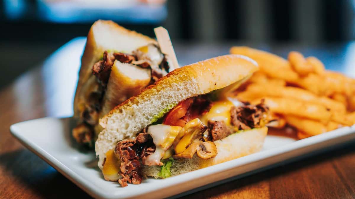 Large grilled hot sandwich with melty cheese and a thick tooth pick to hold it together.