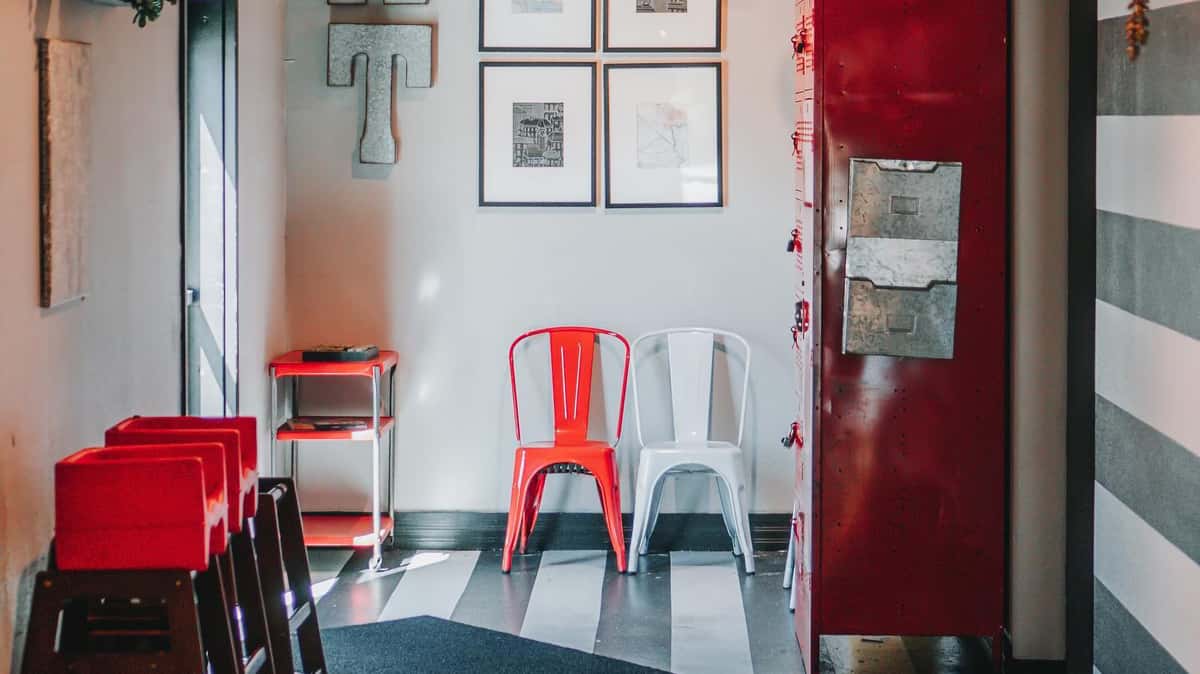 Red and white metal chairs with chic decor, white and black stripe tiling and red metal cabinets.