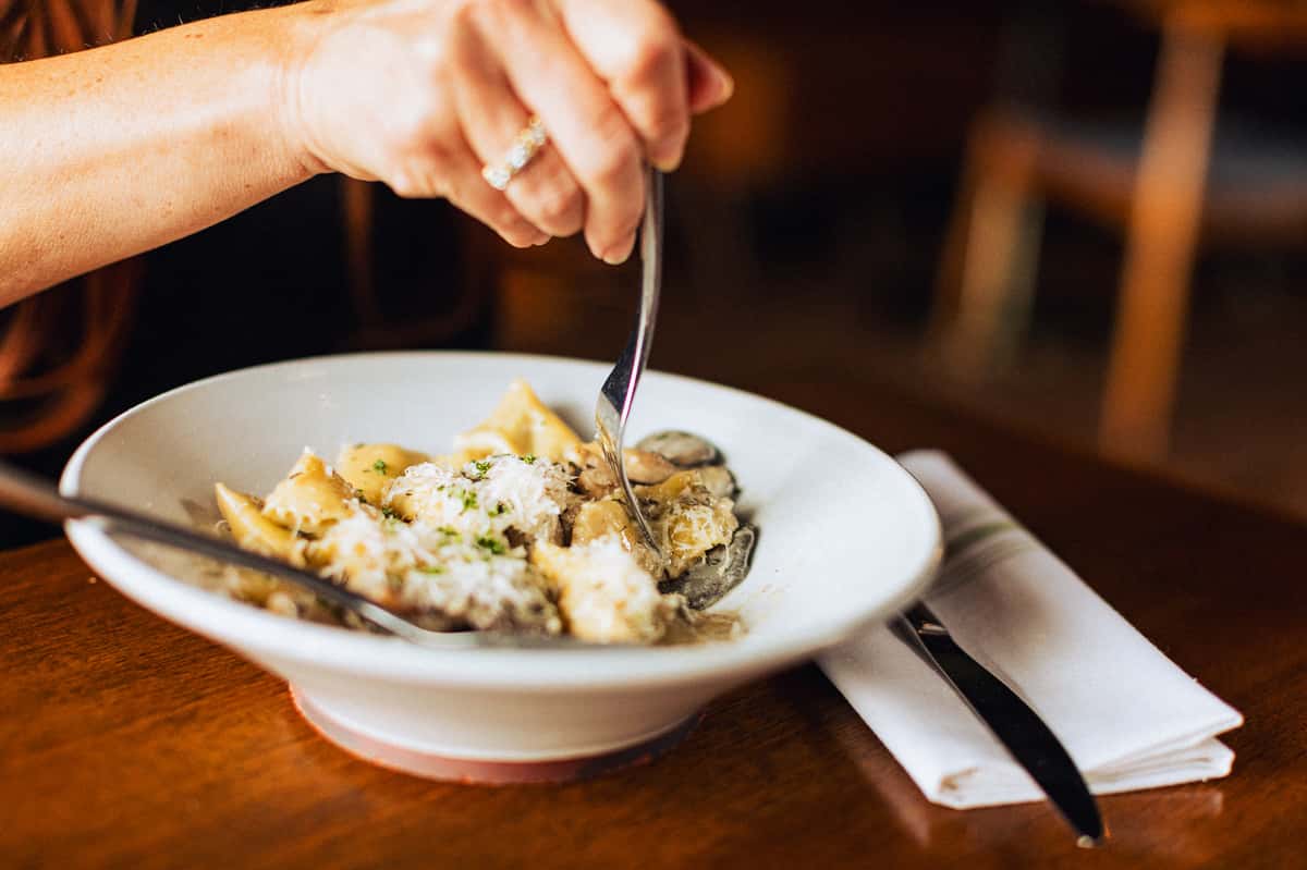 Hand picking up food from a bowl with a fork