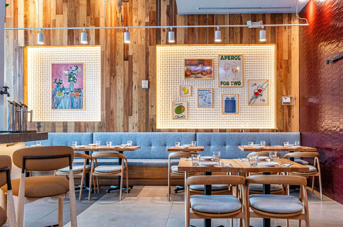 Modern restaurant dining room with wood-paneled walls, booth seating, and neatly arranged tables for guests.