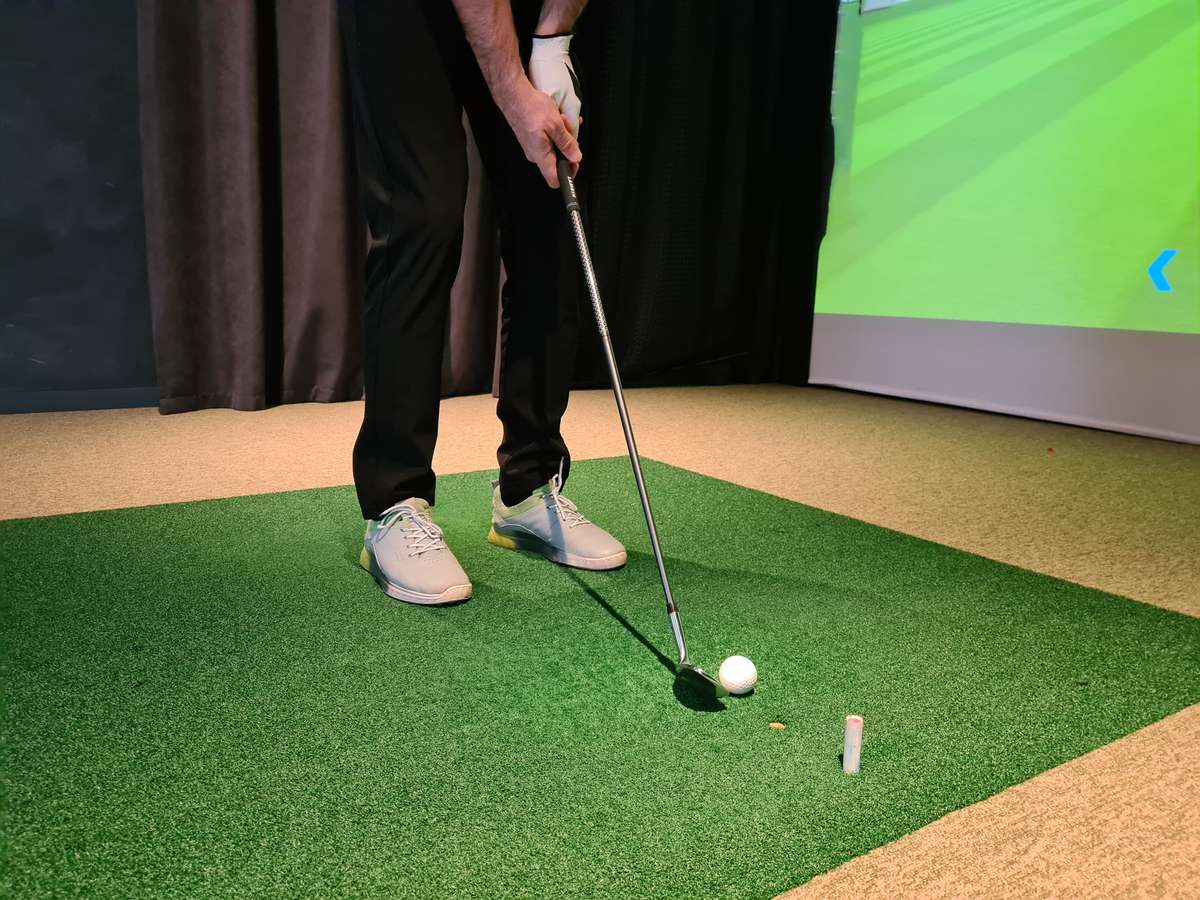 Up close photo of a player using an indoor golf simulator