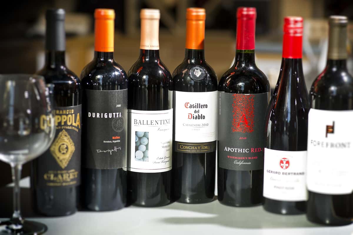 various bottles of red wine with a glass over to the side