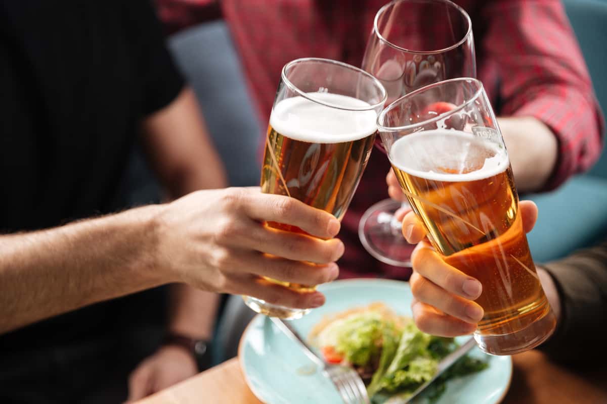 Friends toasting with glasses of beer while enjoying catered appetizers