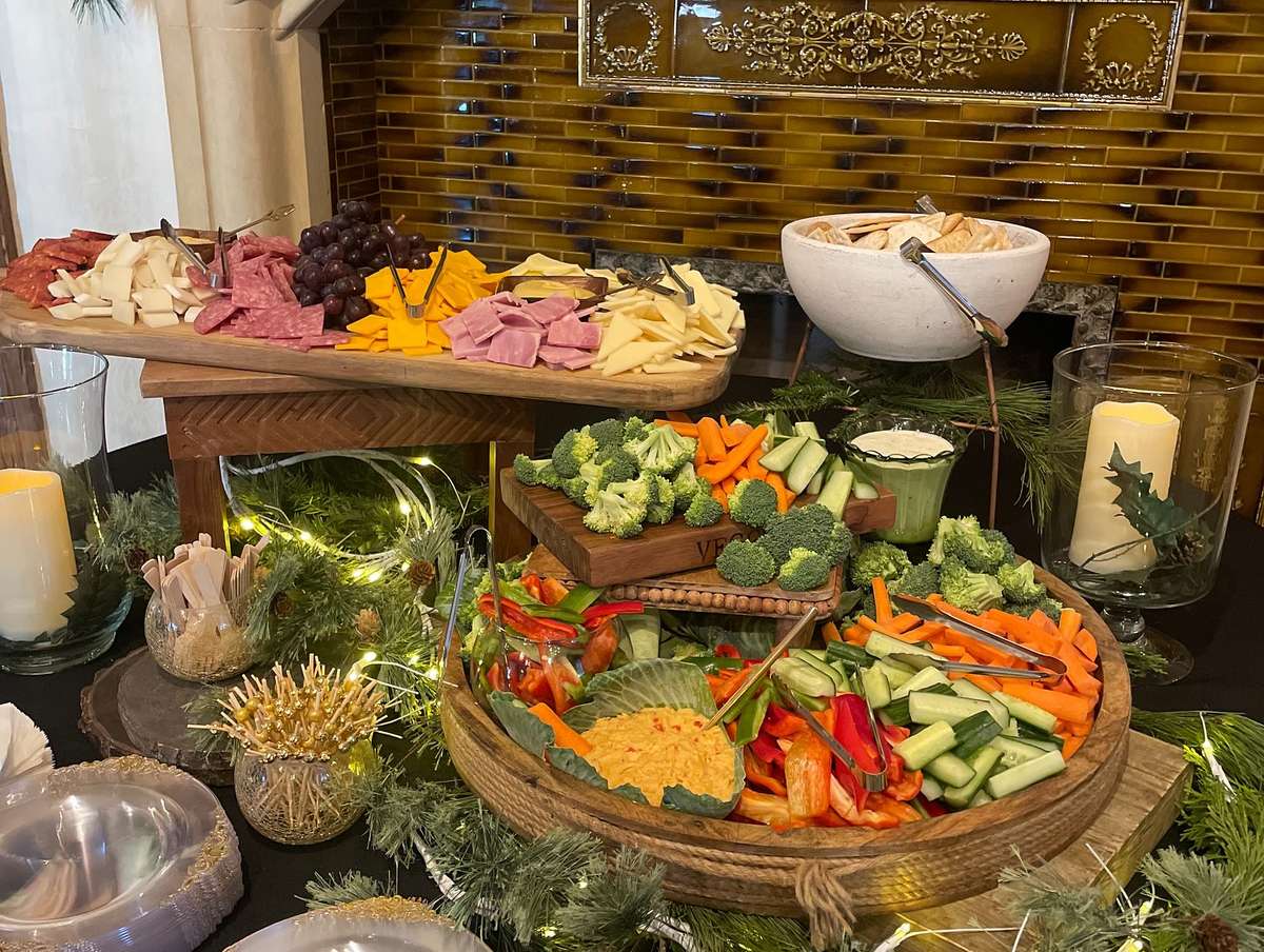 A colorful catering display with fresh vegetables like broccoli and carrots, a shrimp cocktail with lemon, and a bowl of salsa, ideal for weddings and corporate events.