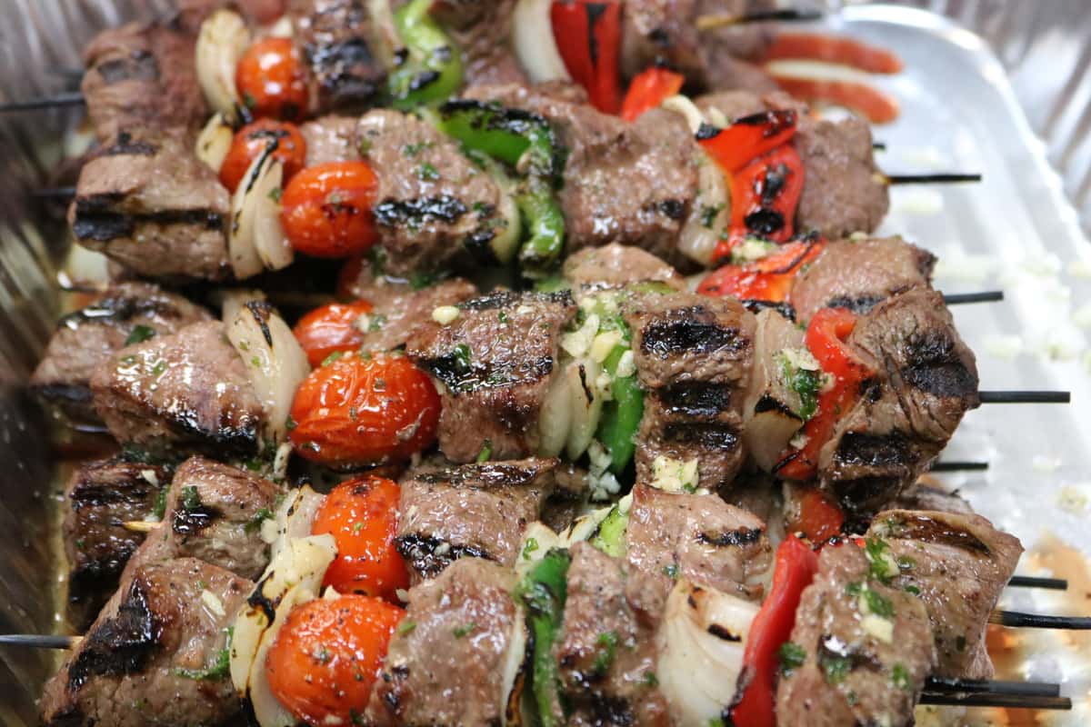 A vibrant platter of grilled skewers featuring tender chunks of meat paired with colorful vegetables like cherry tomatoes, peppers, and onions. Lightly charred and garnished with fresh herbs, the dish looks flavorful, juicy, and perfect for sharing.