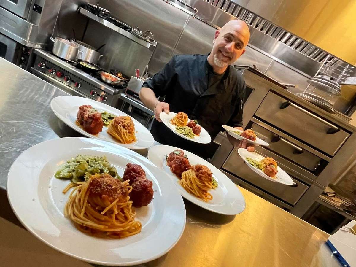 Holding multiple plates of spaghetti and meatballs