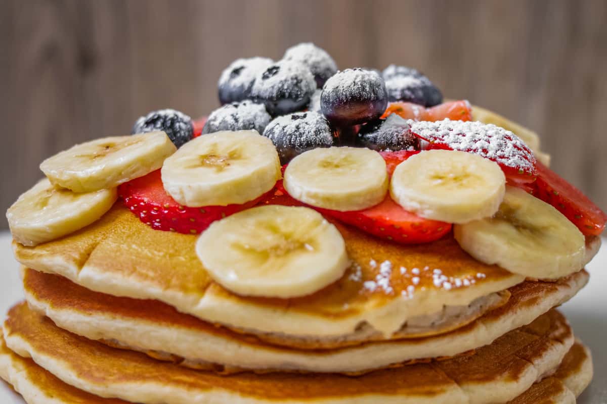 Pancakes and fruit topped with powdered sugar.