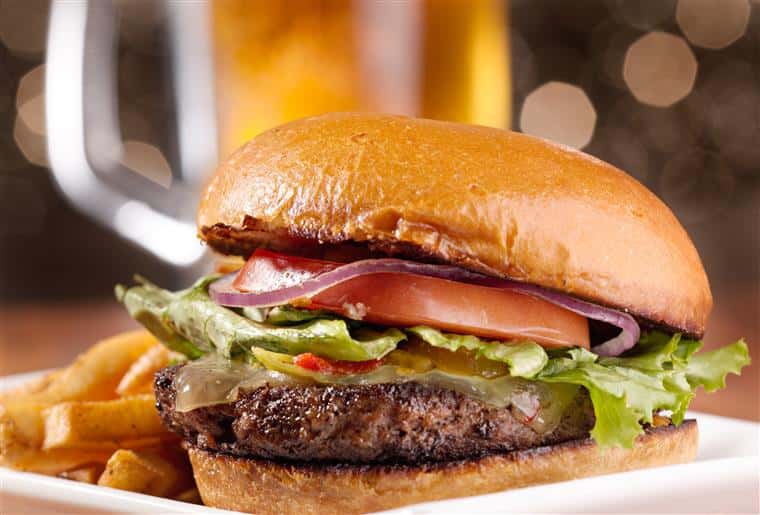 a burger with lettuce, tomato, and onions with a side of fries on a plate