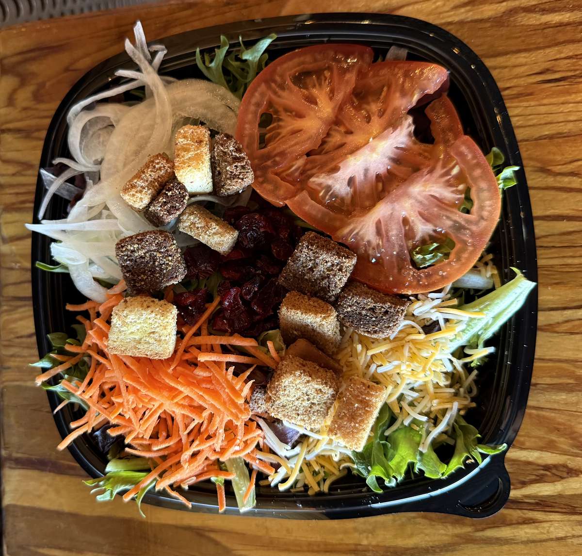 A fresh salad with tomato, shredded carrots, cheese, croutons, cranberries and onion is being served at Main Street Eats.