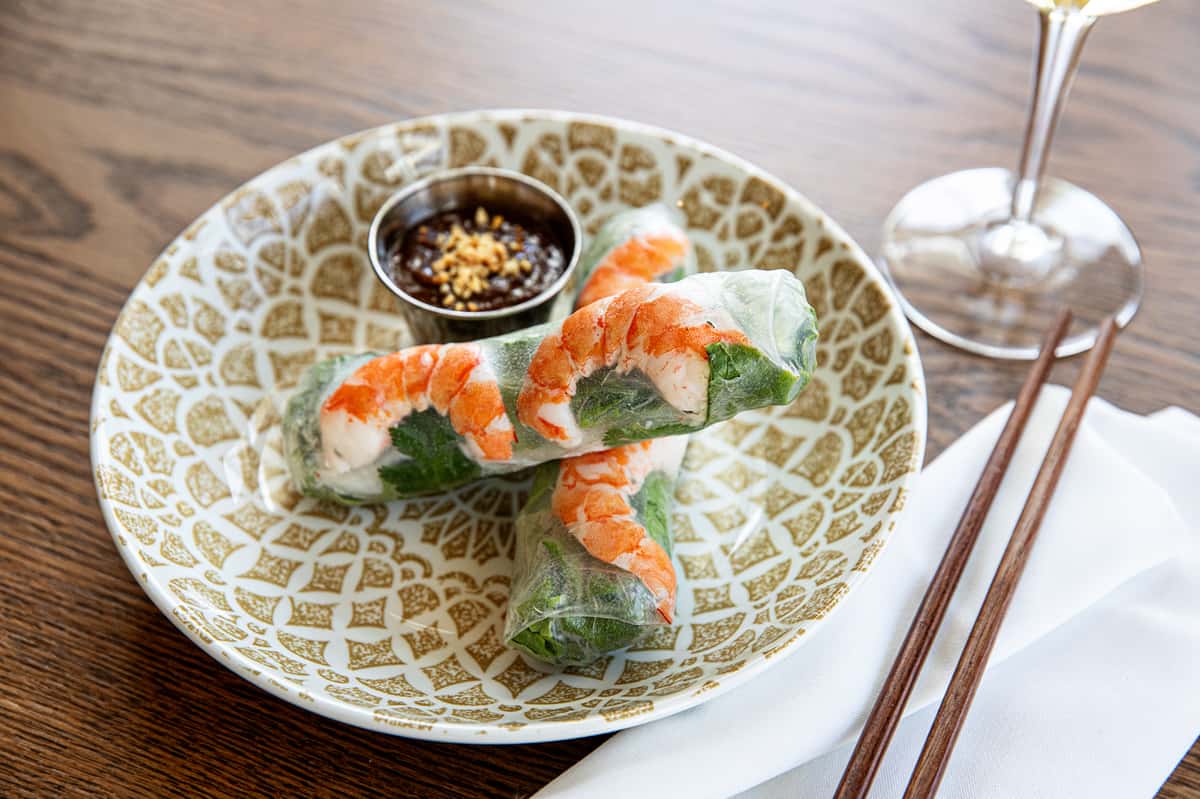 Two spring rolls on a plate with dipping sauce
