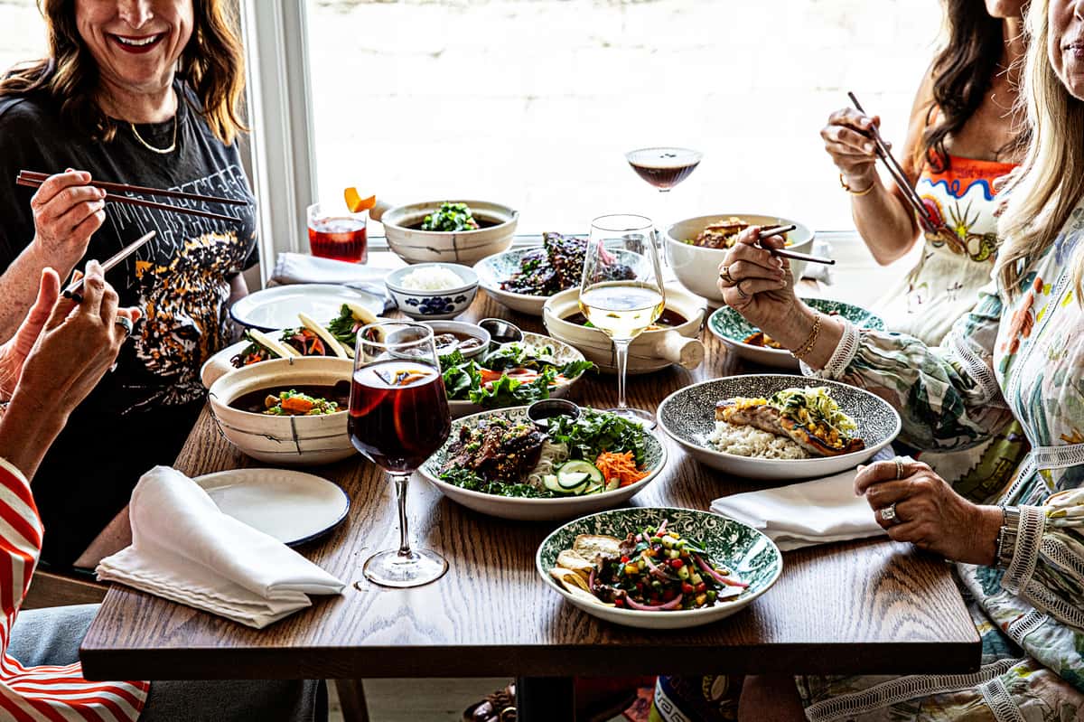 Diners sitting at a table full of drinks and Vietnamese food