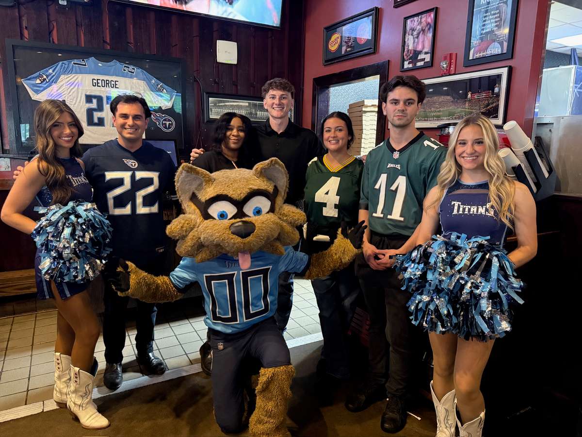 Group of guests posing with a sports mascot at the restaurant