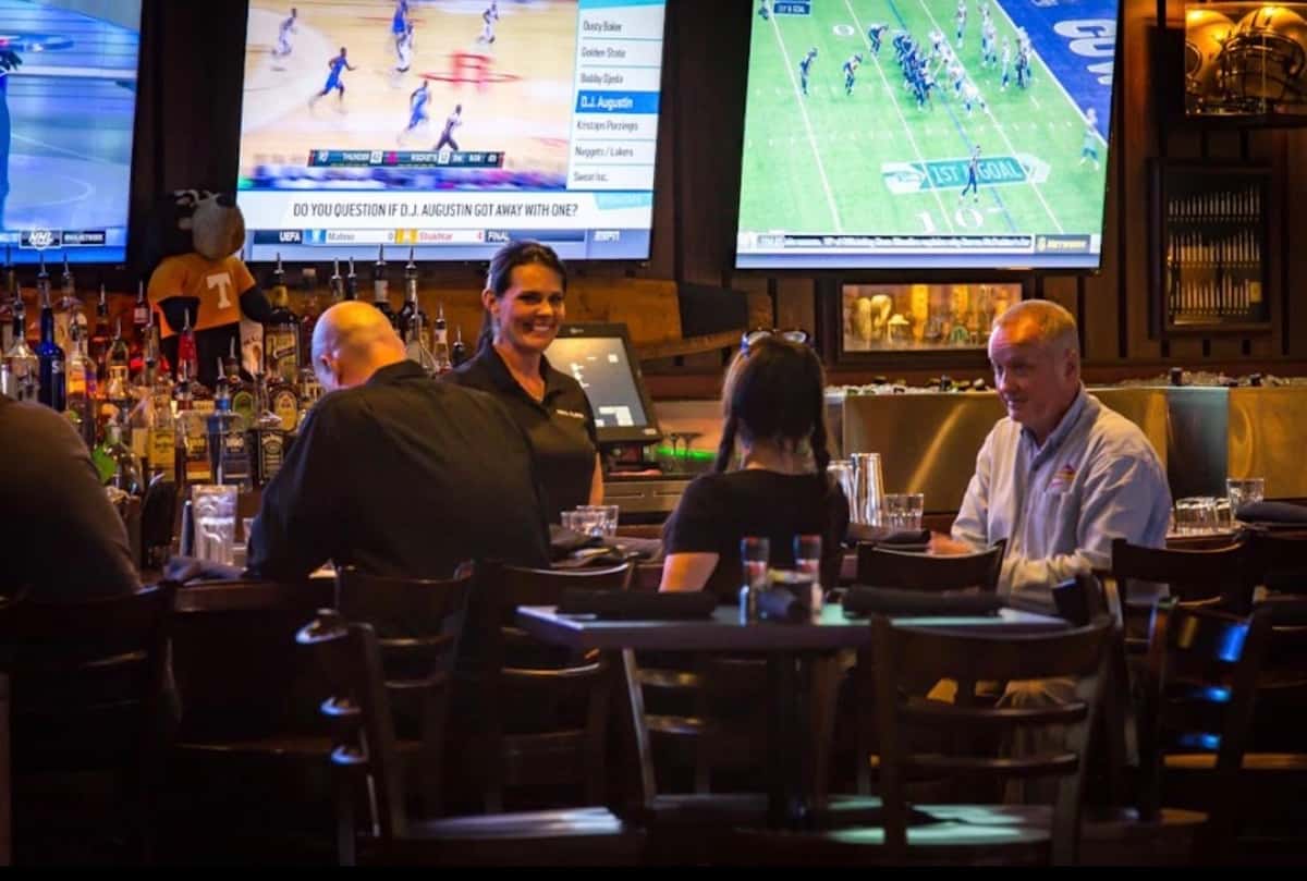 Guests seated at the bar with sports playing on TVs in the background