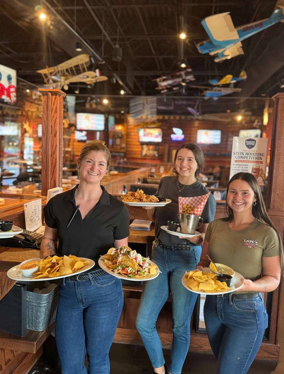 Restaurant staff holding plates of food at the bar