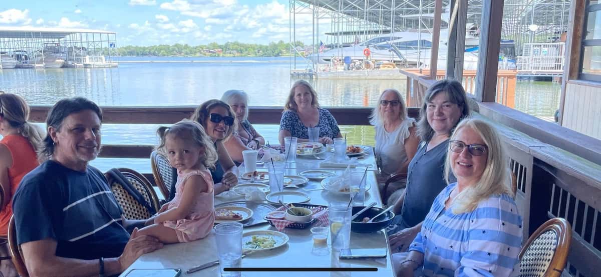 Group dining together at a long table on the waterfront patio