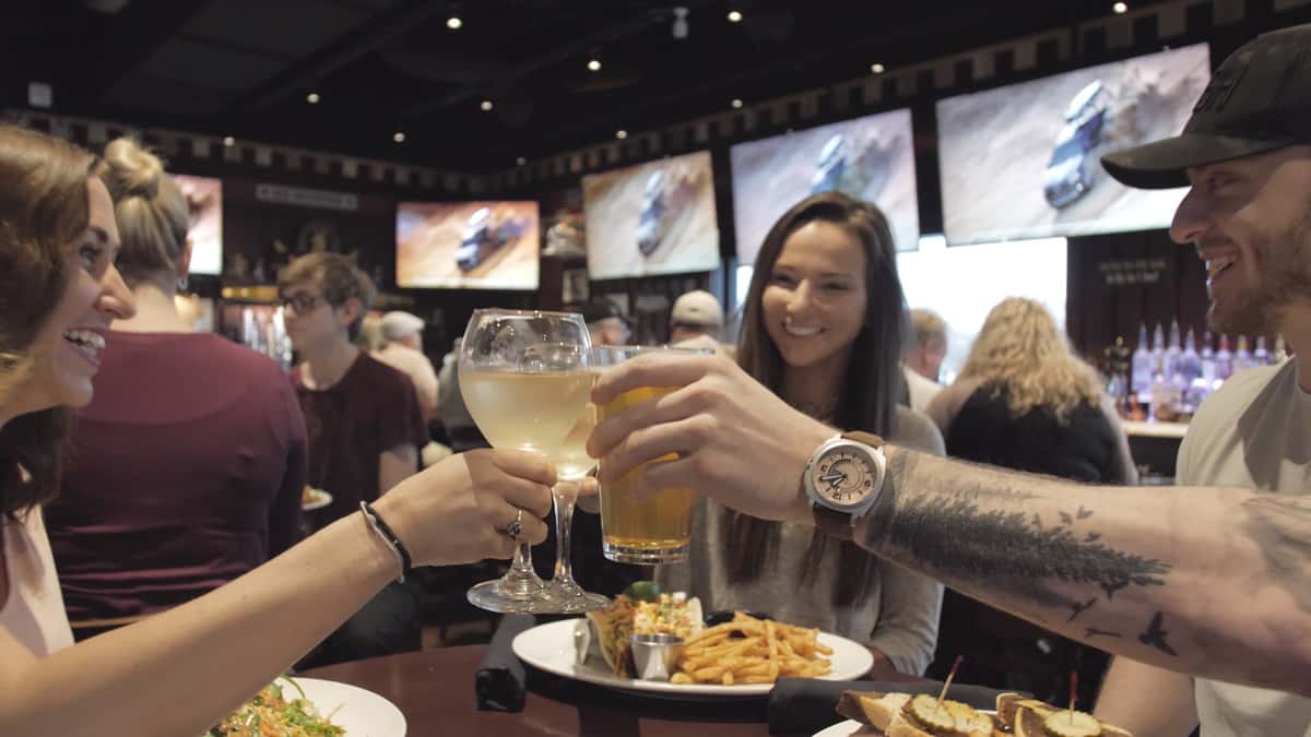 Friends toasting with wine glasses over a table of food at a restaurant