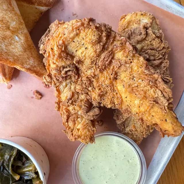 Crispy fried chicken served with toast, greens, and a creamy green dipping sauce.