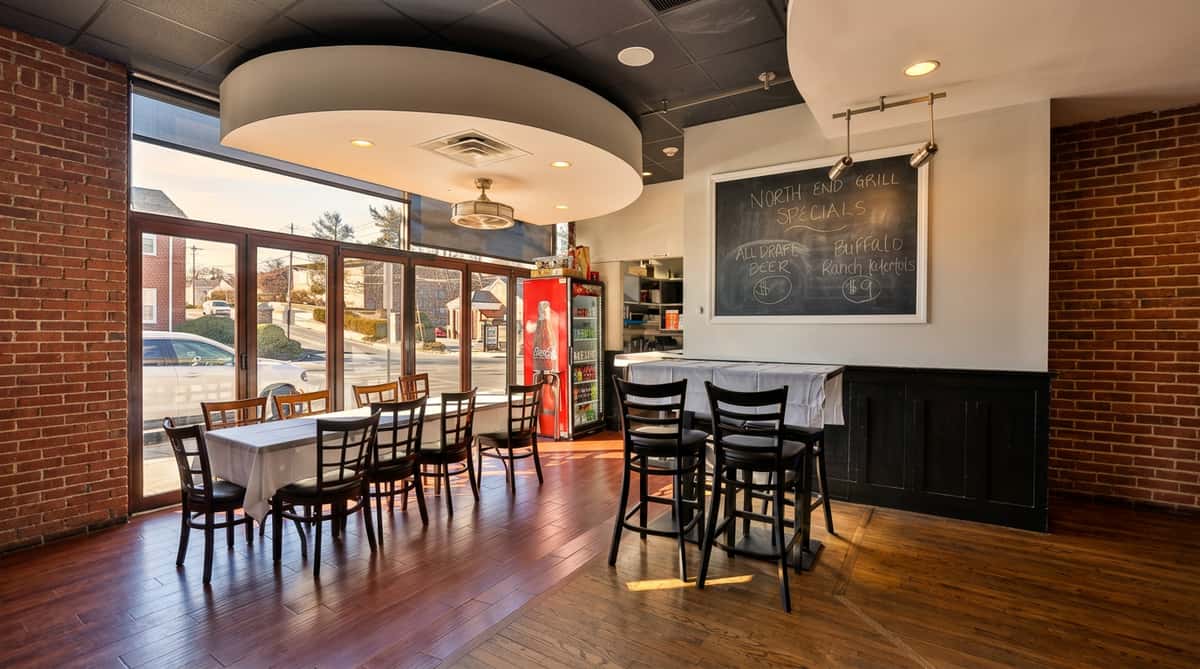 Diner interior with large windows, wooden floors, tables and chairs, a red Coca-Cola fridge, and a specials chalkboard.
