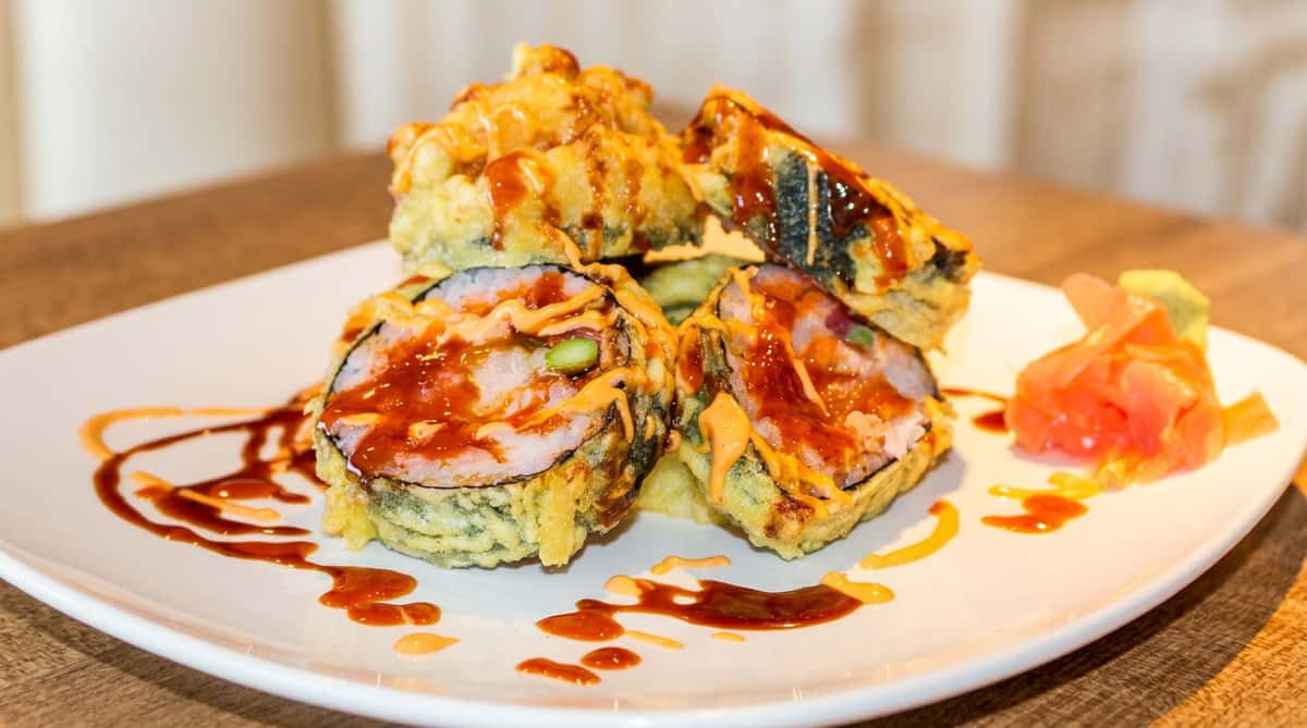 Tempura-fried sushi rolls drizzled with dark and light sauces, served with pickled ginger and wasabi.