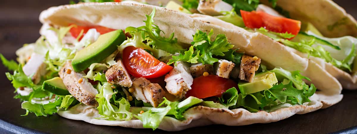 Pita bread sandwiches with grilled chicken meat, avocado, tomato, cucumber